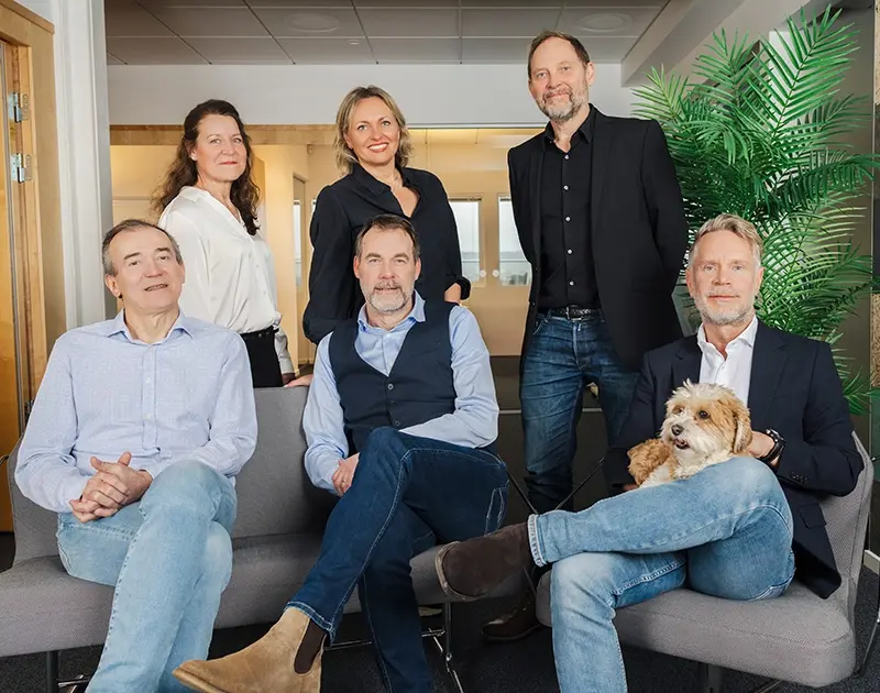 Gruppbild på män, kvinnor och en hund tagen i kontorsmiljö